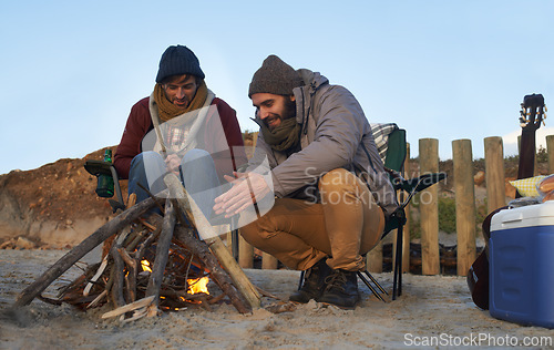 Image of Men, sunset and campfire with warming hands, smile and happy from travel adventure and journey outdoor. Friends, ocean and sea with bonding, hug and vacation by the beach on holiday with fire