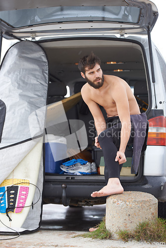 Image of Man, surfer and dressing by car for fitness, exercise or getting ready for waves or tide at beach. Male person or athlete with surfboard and wetsuit with clothing in outdoor preparation by vehicle