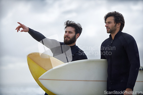 Image of Man, friends and surfer pointing on beach for fitness, sport or waves on shore in outdoor exercise. Young male person or people with surfboard for surfing challenge or hobby on ocean coast in nature