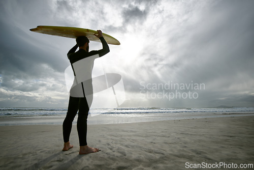 Image of Man, surfer and wetsuit at beach for waves, sport or exercise on sandy shore in outdoor fitness. Rear view of male person or athlete with surfboard for surfing on ocean coast, sea or water in nature