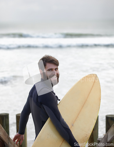 Image of Happy man, portrait and surfer on beach for fitness, sport or waves on shore in outdoor exercise. Young male person with smile and surfboard for surfing challenge or hobby on ocean coast in nature