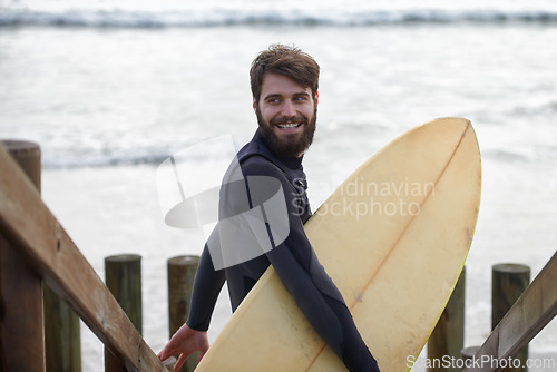 Image of Happy man, surfer and beach by waves for fitness, exercise or extreme sports on outdoor shore. Young male person with smile and surfboard for surfing challenge or hobby at ocean coast, sea or nature