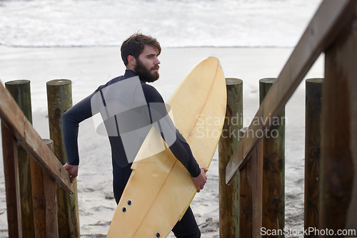Image of Man, surfer and beach by waves in fitness, exercise or extreme sports on outdoor shore. Rear view of male person or athlete with surfboard for surfing challenge or hobby at ocean coast, sea or nature