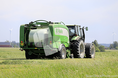 Image of Tractor and Baler Baling Silage on Sunny Day