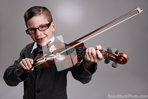 Image of Smile, music and child with violin in studio for practice with suit and glasses for fashion. Happy, style and portrait of young boy kid play string instrument with spectacles by gray background.