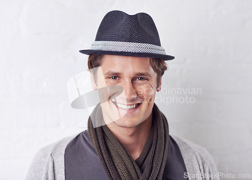 Image of Happy, fashion and portrait of man by wall with casual, cool and trendy outfit for confidence. Smile, handsome and young male person with attractive style and hat standing by white brick background.