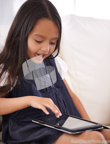 Image of Little girl, child and tablet on sofa for entertainment, movie or online streaming in living room at home. Face of female person or kid browsing or scrolling on technology for reading ebook at house