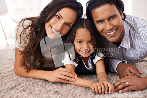 Image of Happy family, portrait and lying on floor for love, bonding or care together at home. Face of mother, father and little girl, daughter or child with smile in living room for holiday weekend at house