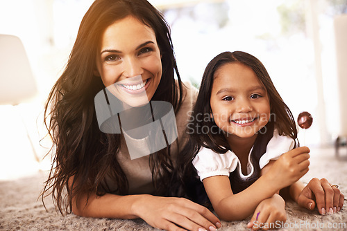 Image of Happy, mom and portrait with child and lollipop on floor in relax for family bonding, love or care together at home. Face of mother, parent and little girl, daughter or kid with smile in living room