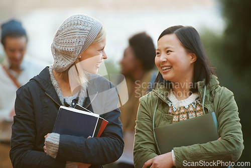 Image of Students, women and friends outdoor on campus for university, conversation and walking to class with smile. College, communication and books for studying, education and academic growth with talk