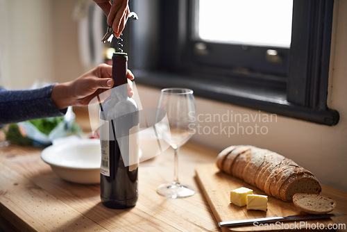 Image of Hands, opening wine bottle and dinner on table, evening meal with corkscrew and glass, person preparing to drink for enjoyment. Alcoholic beverage, tools with cooking for dining and bread in kitchen