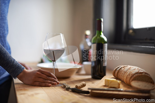 Image of Hand, red wine in glass and bread on table, dinner meal prep and drink to relax while cooking. Person at home, food and beverage to enjoy for nutrition, health and wellness with alcohol and supper