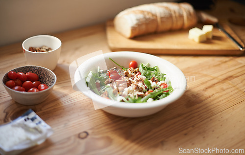 Image of Healthy, salad and lunch on table in kitchen closeup with bread for nutrition and diet in home. Tomato, lettuce and cooking with nuts in food with bowl on counter for dinner and meal prep in house