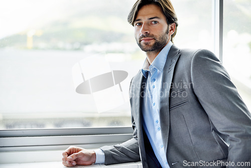 Image of Business man, entrepreneur and serious by window in portrait, confident and professional in office. Male person, employee and pride for career at startup company, professional and expert at workplace