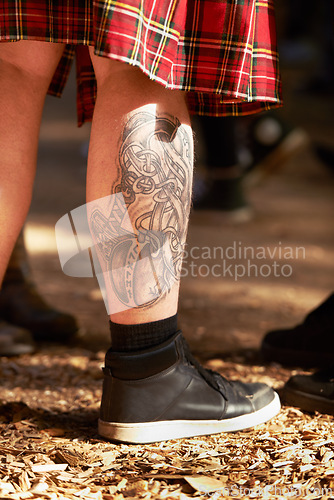 Image of Closeup, man and leg with tattoo, outdoor and festival with sneakers and weekend break. Person, outside and guy with a shoes and summer for fun and getaway trip with art and ground with sunshine