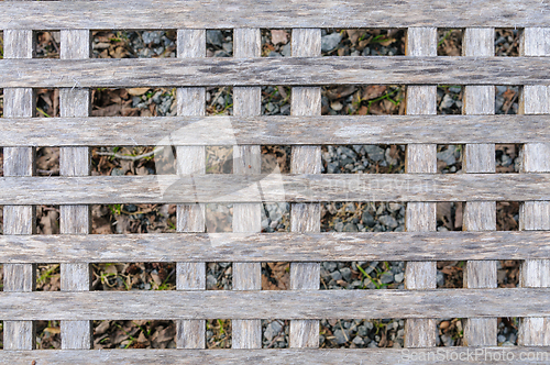Image of Close-up view of a wooden lattice structure over gravel ground