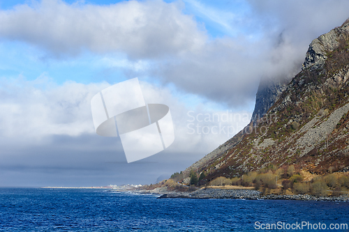 Image of Majestic cliffside by the ocean with cloud-covered mountain peak