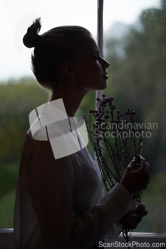 Image of Female person, flowers and window for in home, dark room and alone aesthetic for contemplation or artistic. Women, dim light and morning with thinking, creative and mysterious style for loneliness