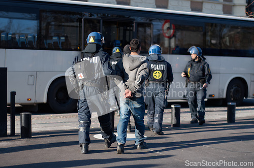 Image of Police officer, arrest and person in street for crime, safety and bus for crowd control in city. People, law enforcement and vehicle for danger, warning and transportation on urban road in Copenhagen