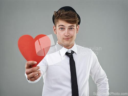 Image of Portrait, man and heart in studio holding greeting card for Valentines day, romantic and mockup. Hopeful, trendy guy and gen z hipster with shirt, tie and smile against light grey background