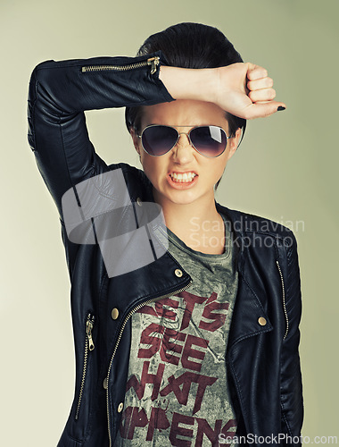 Image of Woman, studio and angry with punk, fashion and style for confidence, modern and contemporary. Rockstar, leather jacket and sunglasses for rebel, model and empowerment for attitude, pose and portrait