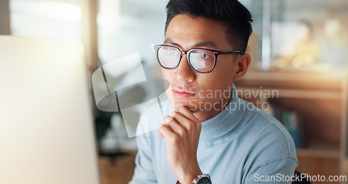 Image of Man at computer, glasses and reflection, thinking and reading email, review or article at digital agency. Internet, research and Asian businessman at tech startup with report, networking or feedback.