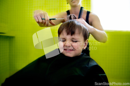 Image of Kid, boy and hairdresser with haircut at salon for grooming, hairstyle and grimace with scissors. Barber, person and child for hair treatment, haircare and hairdressing with comb, happy and grimace