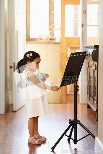 Image of Flute, girl and child playing in home for learning, education and reading music sheet to practice performance. Art, flutist and kid with talent, creative or hobby with instrument for sound at lesson