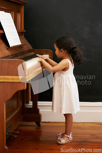Image of Piano, girl and toddler in home for learning, practice and classical education with musical notes. Training, melody and kid with talent, creative or hobby with instrument, child development or skill