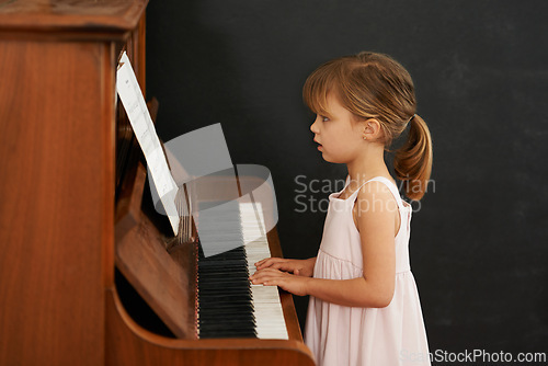 Image of Piano, reading and kid in home for learning, practice and classical education with musical notes. Training, melody and girl with talent, creative or hobby with instrument, child development or skill