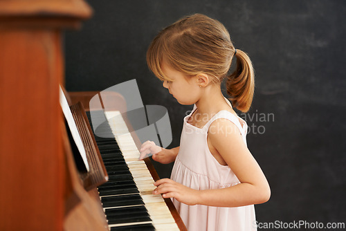 Image of Piano, playing and kid in home for learning, practice and classical education with musical notes. Training, melody and girl with talent, creative or hobby with instrument, child development or skill