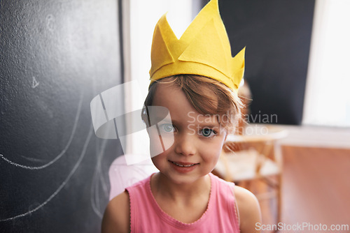 Image of Portrait, paper crown and child with smile for birthday celebration at kindergarten in Germany. Kid, female student or girl beaming in classroom with blackboard for party, fun and play inside