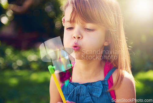 Image of Young girl, backyard and blowing pinwheel, garden and enjoying freedom of outside and fun. Pretty little child, outdoor and summer for playing, toy and windmill for holidays and nature sunshine