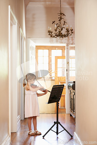 Image of Violin, girl and child playing in home, learning and practice for education, music or performance. Art, fiddle and kid with bow for talent, creative or hobby in house with acoustic string instrument