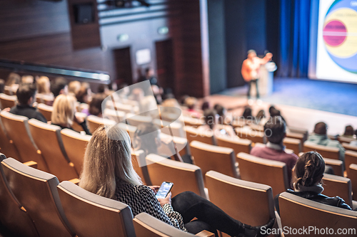 Image of Speaker giving a talk in conference hall at business event. Rear view of unrecognizable people in audience at the conference hall. Business and entrepreneurship concept.