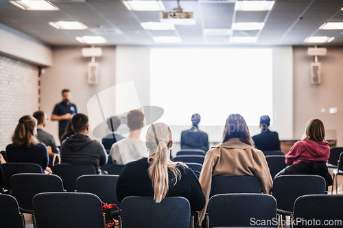 Image of Speaker giving a talk in conference hall at business event. Rear view of unrecognizable people in audience at the conference hall. Business and entrepreneurship concept.