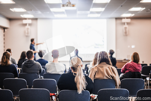 Image of Speaker giving a talk in conference hall at business event. Rear view of unrecognizable people in audience at the conference hall. Business and entrepreneurship concept.
