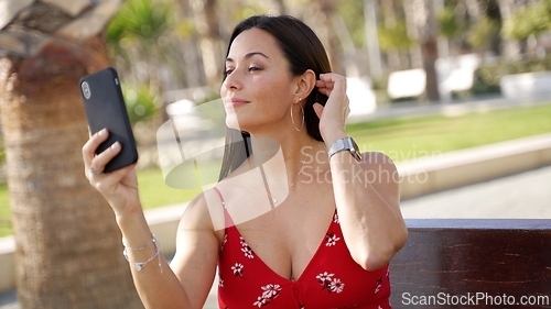 Image of Woman in Red Dress Taking Selfie in Sunny Park