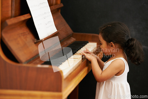 Image of Piano, kid and toddler in home for learning, practice and classical education with musical notes. Training, melody and girl with talent, creative or hobby with instrument, child development or skill