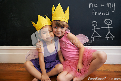 Image of Little girls, friends and portrait with embrace, crown and smile for love and happiness. Children, youth and hug for face, fun and bonding with blackboard and fairy princess costume for dress up