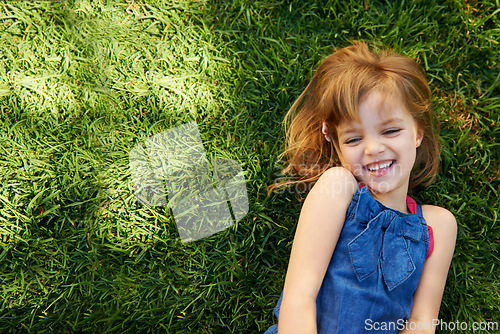 Image of Child, grass and smile from above for relax holiday in countryside for summer vacation, nature or park. School kids, and happy on garden lawn in California environment for outdoor, sunshine or mockup