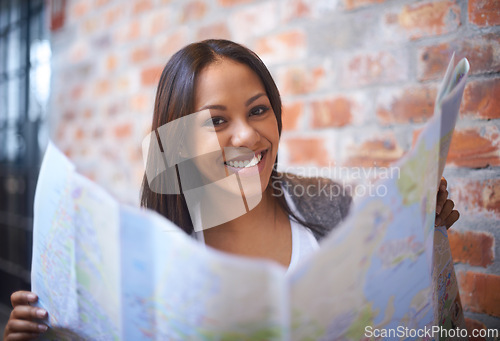 Image of Happy woman, portrait and reading map for travel, immigration or commute by a brick wall. Face of female person, tourist or traveler with smile for direction, geographic document or world coordinates