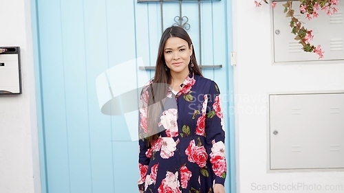 Image of Confident Woman in Floral Dress Standing by Blue Door