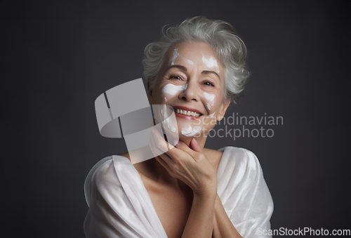 Image of Elderly woman applies facial cream, gracefully embracing a skincare routine