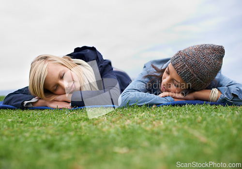 Image of Sleeping, grass and women relax in field with smile, happy and resting on weekend outdoors. Friends, countryside and people lying in meadow for bonding on holiday, vacation and adventure in nature