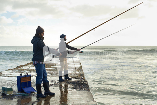 Image of Fishing, friends and travel with men at beach for adventure, holiday and hobby break. Sunset, calm and patience with male fisherman and casting rod pole in nature for recreation, view and vacation