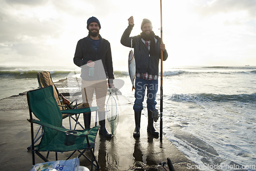Image of Happy, portrait and men fishing at ocean with pride for tuna catch on pier at sunset. Fisherman, friends and smile holding fish and rod in hand on holiday, adventure or vacation in nature at sea