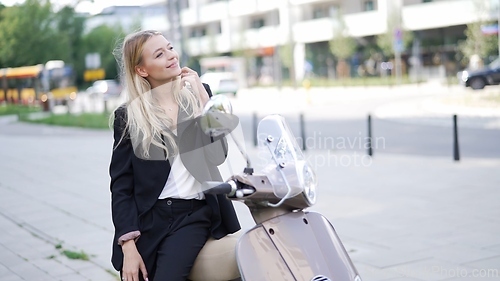 Image of Businesswoman Relaxing on Scooter in Urban Setting