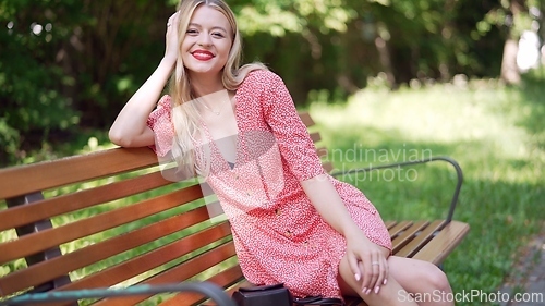 Image of Happy Young Woman Smiling on Park Bench in Summer