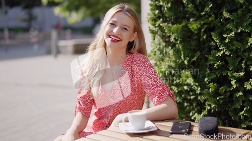 Image of Smiling Woman Enjoying Coffee Outdoors on a Sunny Day
